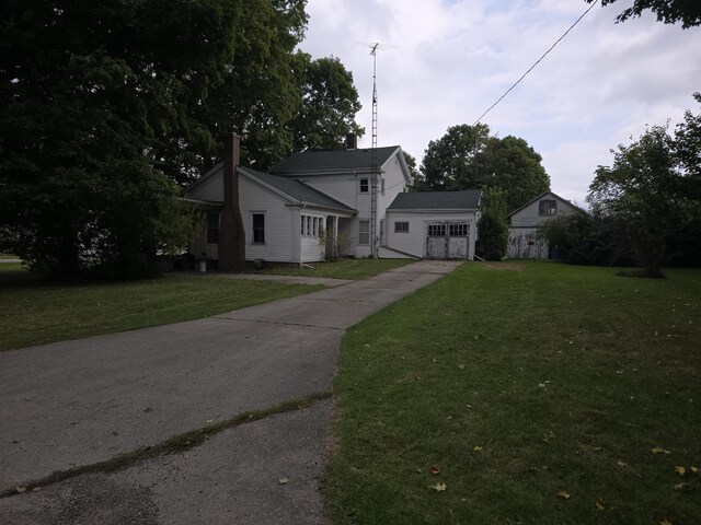 103 S Railroad St, Allen, MI 49227 - view of front of property featuring a garage, a front lawn, concrete driveway, and a chimney