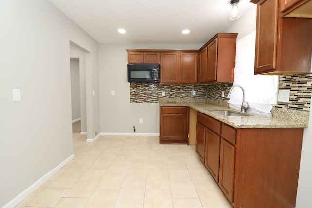 kitchen featuring backsplash, light stone countertops, sink, and light tile patterned floors