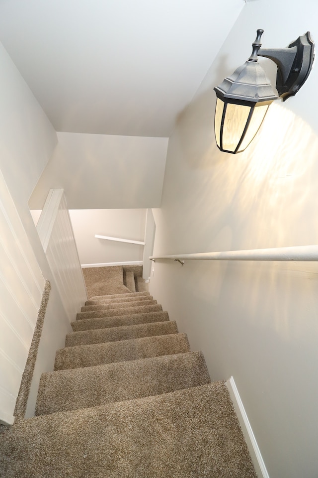 staircase featuring carpet floors and lofted ceiling