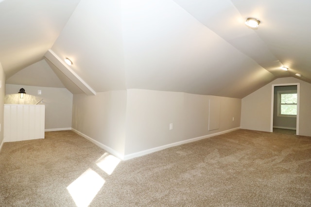 additional living space featuring carpet flooring and vaulted ceiling