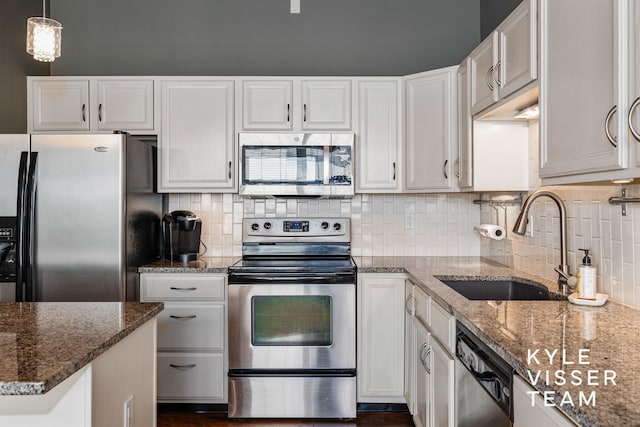 kitchen featuring white cabinetry, sink, stainless steel appliances, and decorative light fixtures