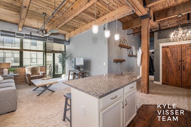 kitchen featuring beam ceiling, wooden ceiling, carpet, decorative light fixtures, and white cabinets