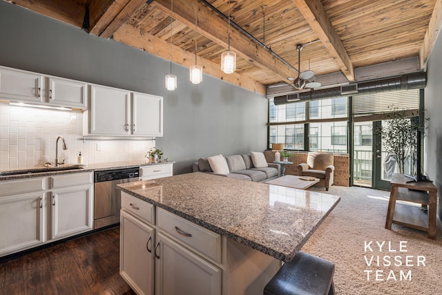 kitchen with hanging light fixtures, dark hardwood / wood-style flooring, stainless steel dishwasher, dark stone counters, and white cabinets