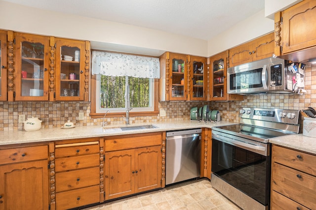 kitchen featuring stainless steel appliances, light stone counters, tasteful backsplash, and sink