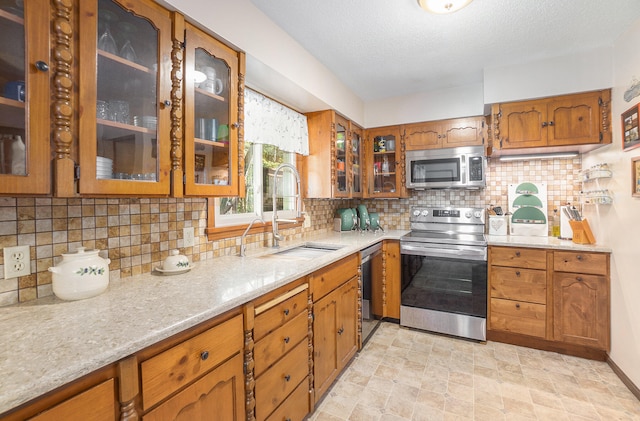 kitchen featuring a textured ceiling, sink, stainless steel appliances, and tasteful backsplash