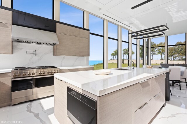 639 Sul Lago Ave S, Benton Harbor, MI 49022 - kitchen with modern cabinets, wall chimney range hood, double oven range, light marble finish floors, and expansive windows
