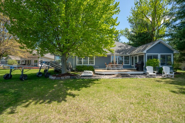 rear view of property featuring a wooden deck, a sunroom, and a yard