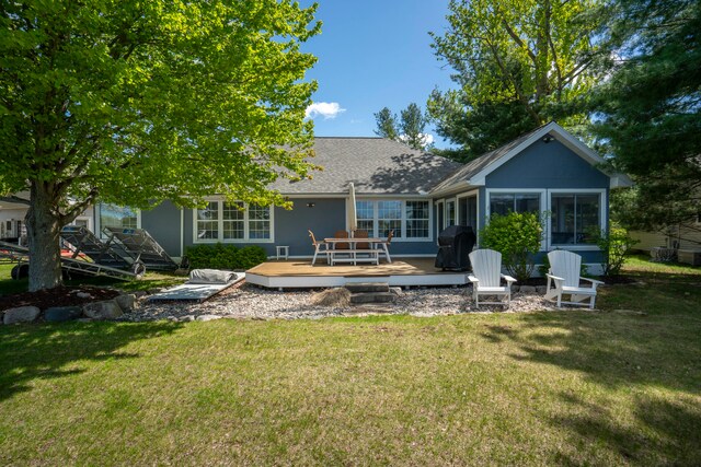 rear view of property featuring a deck, a lawn, and a sunroom