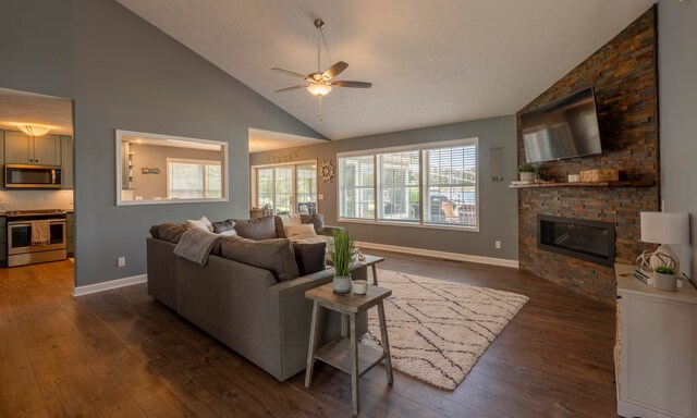 living room with dark hardwood / wood-style flooring, ceiling fan, a fireplace, and high vaulted ceiling