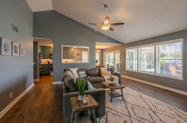 living room featuring ceiling fan with notable chandelier, dark wood-type flooring, and a wealth of natural light