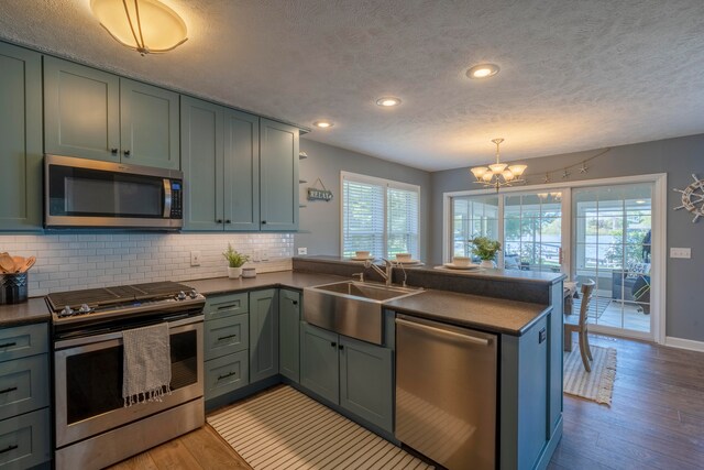 kitchen with kitchen peninsula, a wealth of natural light, light hardwood / wood-style flooring, and stainless steel appliances