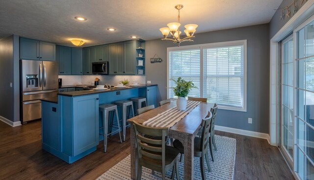 kitchen featuring dark wood-type flooring, kitchen peninsula, a chandelier, pendant lighting, and appliances with stainless steel finishes