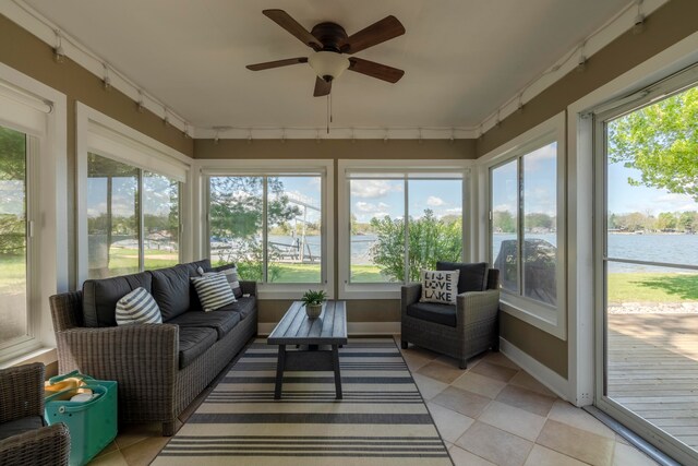 sunroom with rail lighting, a water view, ceiling fan, and a healthy amount of sunlight