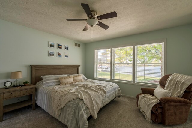 bedroom with ceiling fan, dark carpet, and a textured ceiling