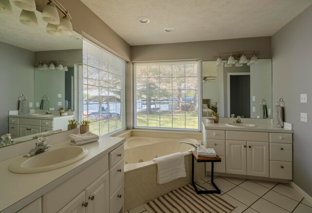 bathroom with tile patterned floors, a tub to relax in, vanity, and a textured ceiling