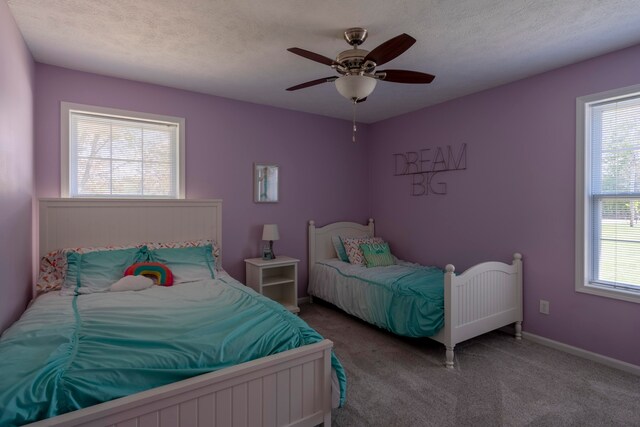 carpeted bedroom featuring multiple windows, ceiling fan, and a textured ceiling