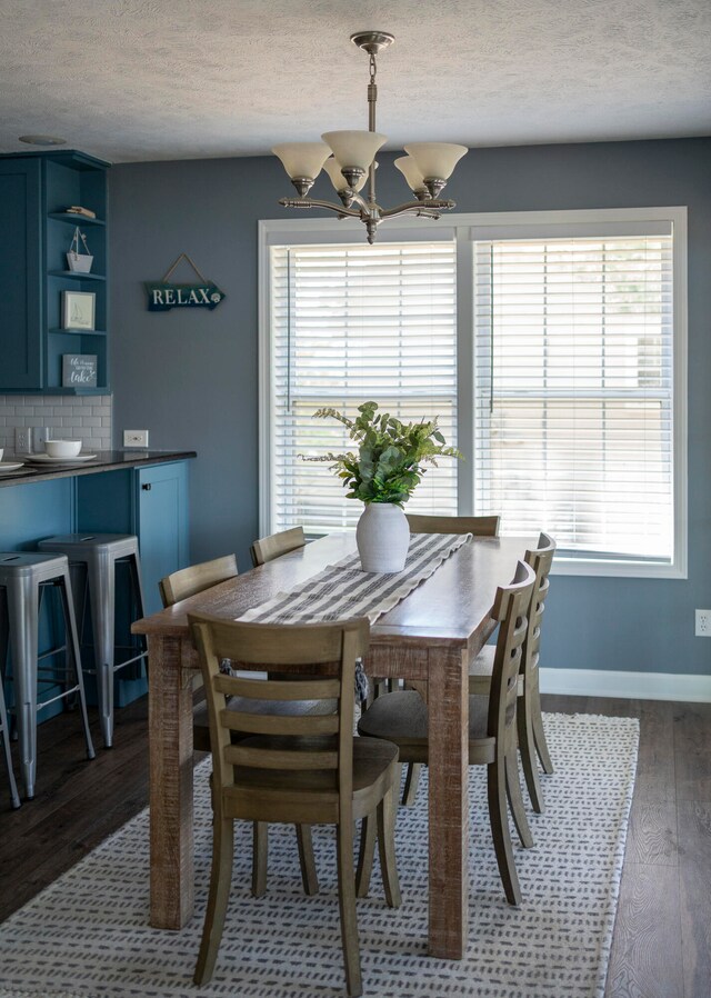 dining space with hardwood / wood-style floors, a textured ceiling, and a notable chandelier