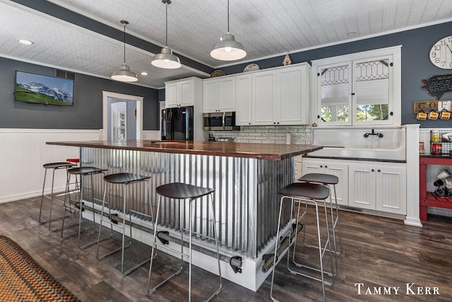 kitchen featuring wood counters, black fridge, white cabinetry, and decorative light fixtures