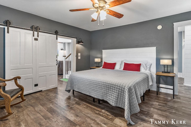 bedroom with a barn door, a closet, ceiling fan, and dark wood-type flooring