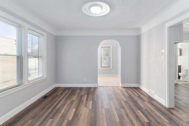 empty room with dark hardwood / wood-style floors and a healthy amount of sunlight