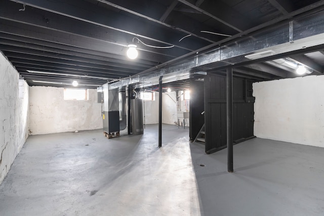 basement featuring sink, heating unit, and water heater