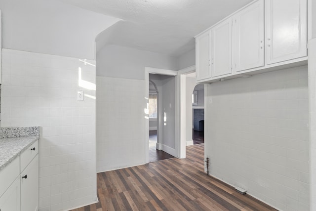 kitchen featuring white cabinets, dark hardwood / wood-style flooring, tile walls, and a textured ceiling