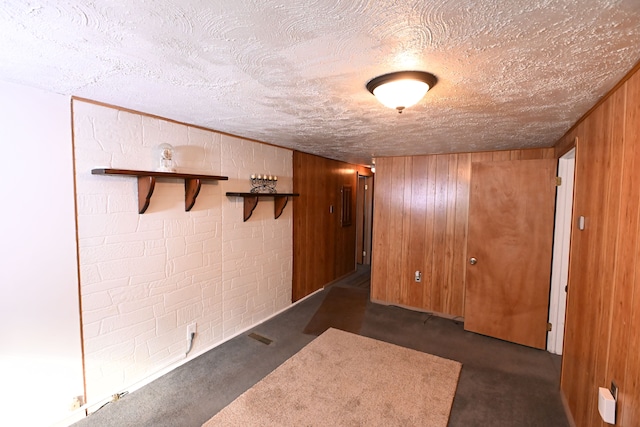 hallway with wooden walls and a textured ceiling