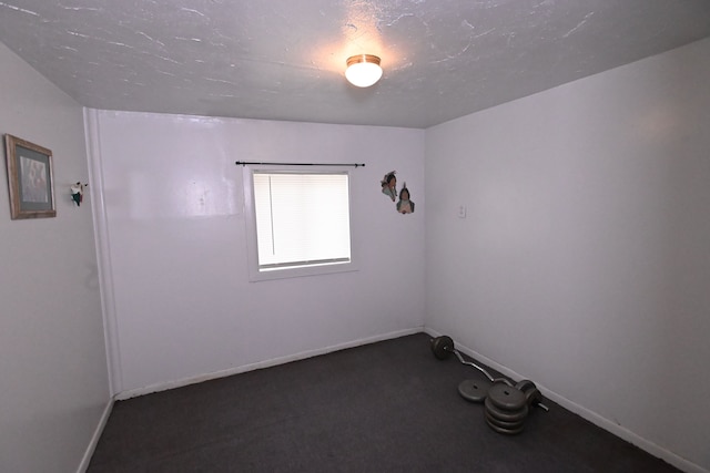 unfurnished room featuring a textured ceiling and dark colored carpet