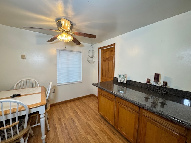 kitchen featuring dark stone countertops, ceiling fan, and light hardwood / wood-style flooring