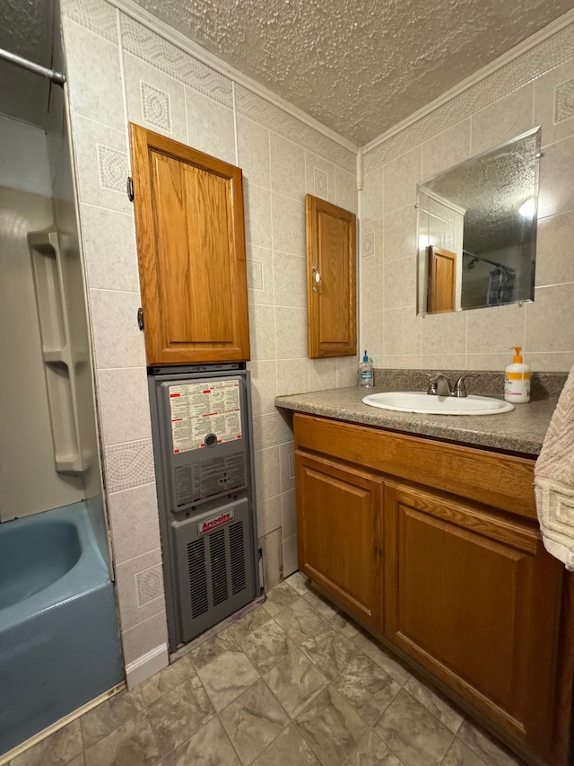 bathroom featuring a textured ceiling, vanity, and tile walls