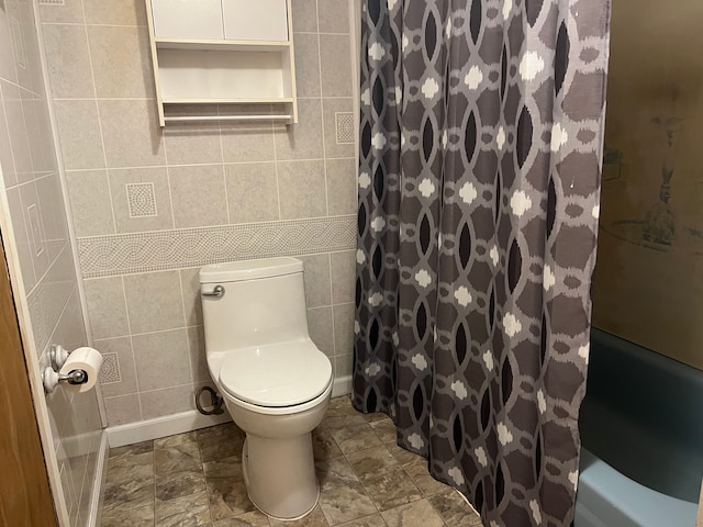 bathroom with curtained shower, toilet, and tile walls