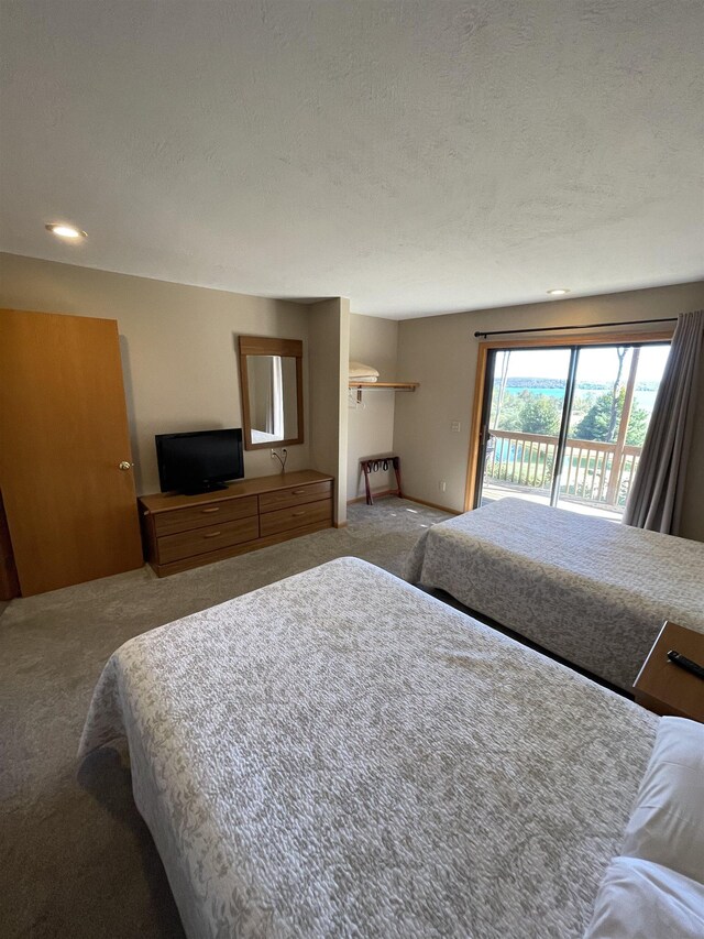 737 Maplewood Ln, Kewadin, MI 49648 - carpeted bedroom featuring access to exterior and a textured ceiling