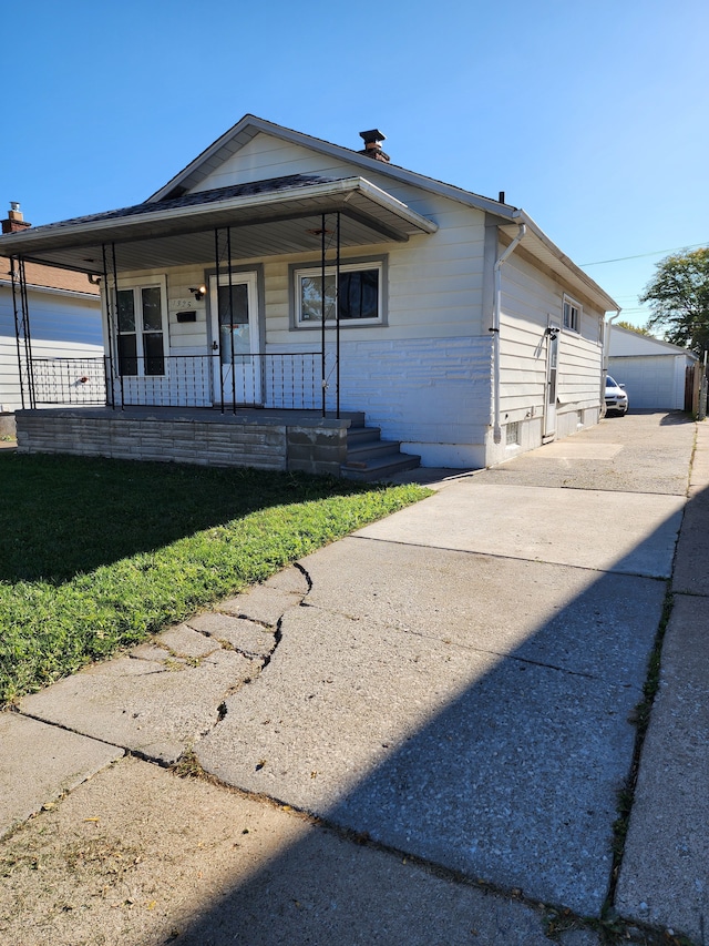 view of front of home with an outbuilding, a front lawn, a porch, and a garage