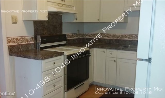 kitchen with white cabinets, dark stone countertops, and white appliances