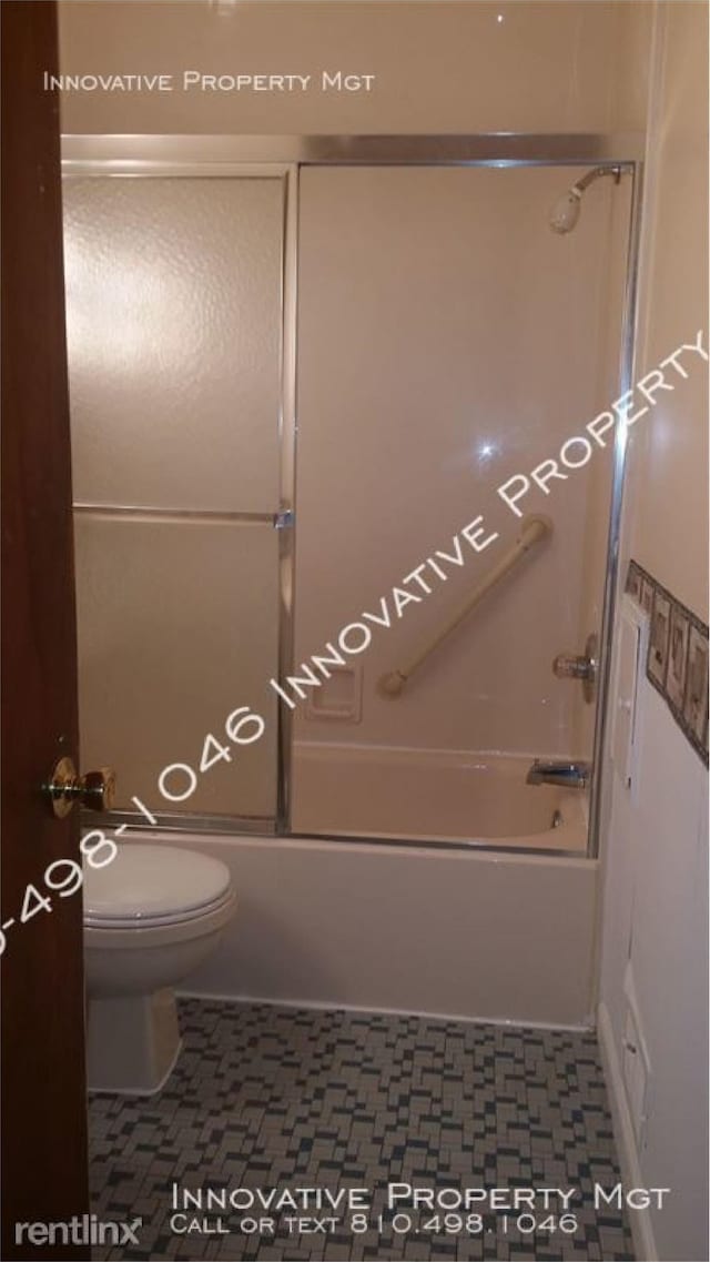 bathroom featuring shower / bath combination with glass door, tile patterned floors, and toilet