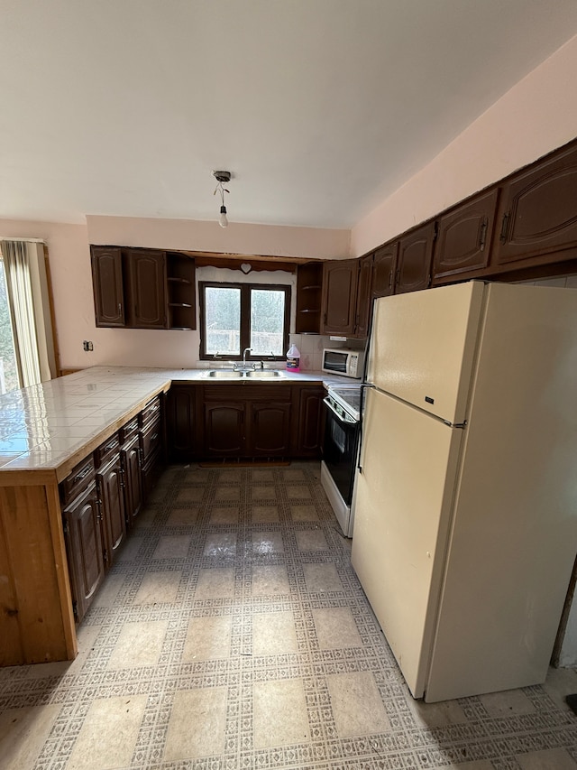 kitchen with kitchen peninsula, dark brown cabinets, white appliances, and sink