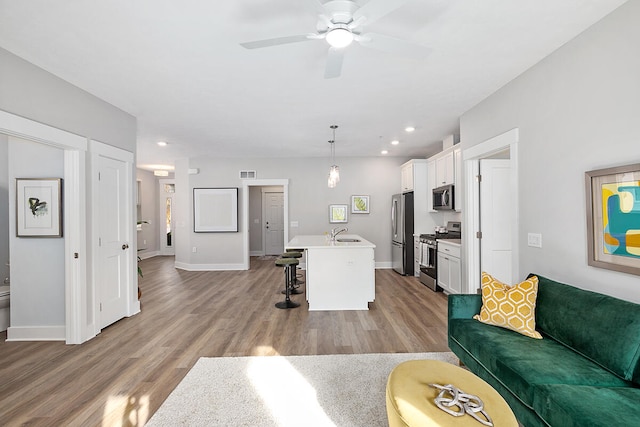 living room featuring ceiling fan, light wood-type flooring, and sink