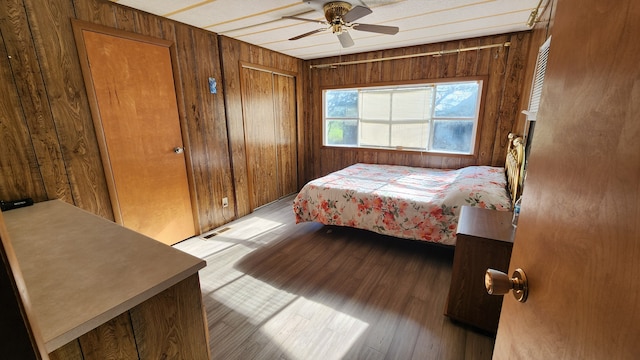 bedroom featuring light hardwood / wood-style flooring, ceiling fan, and wooden walls