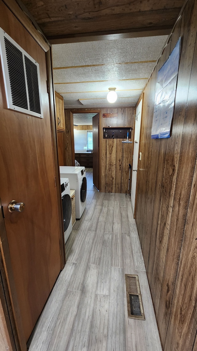 washroom featuring washer and dryer, light hardwood / wood-style floors, and wooden walls