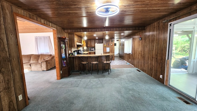 bar featuring wood walls, wooden ceiling, and white refrigerator