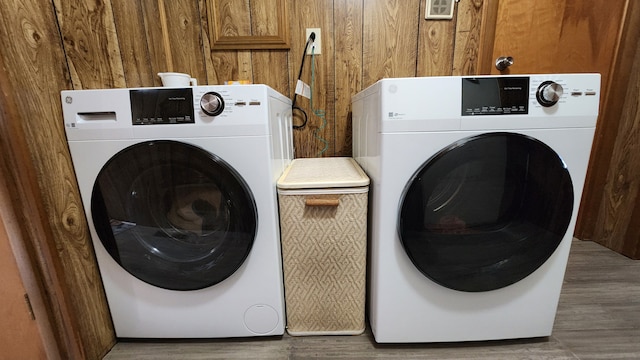 laundry room featuring washer and clothes dryer, hardwood / wood-style flooring, and wooden walls