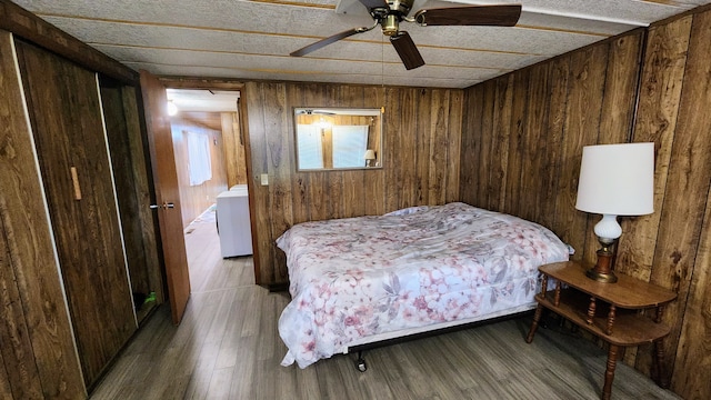 bedroom featuring hardwood / wood-style floors, a closet, ceiling fan, and wooden walls