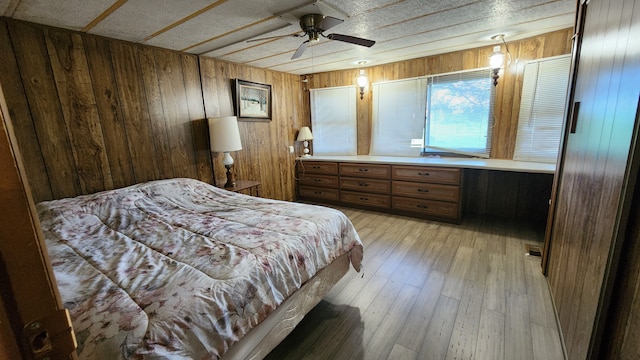 bedroom featuring wood walls, ceiling fan, and light wood-type flooring