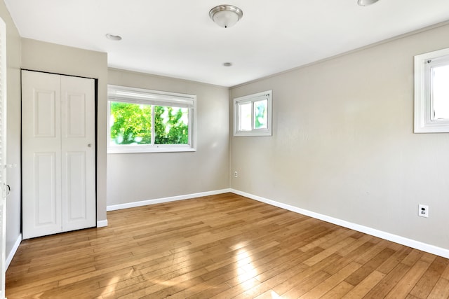 unfurnished bedroom featuring light hardwood / wood-style flooring, a closet, and crown molding