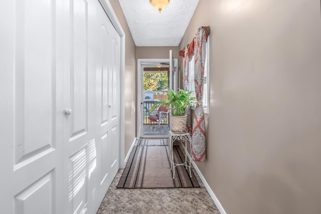 doorway to outside with carpet flooring and a textured ceiling