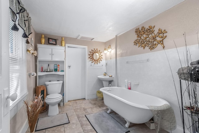 bathroom with tile patterned flooring, a textured ceiling, toilet, and a bathtub