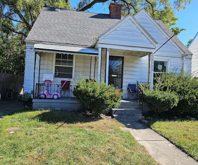 bungalow featuring covered porch and a front lawn