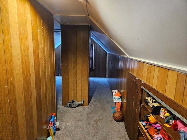 corridor with wooden walls, light carpet, and vaulted ceiling