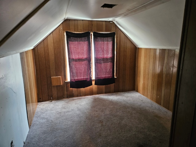 additional living space featuring wood walls, carpet floors, and vaulted ceiling