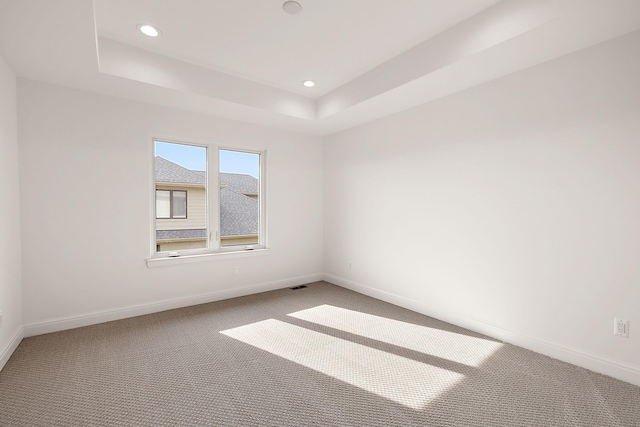 carpeted empty room with a tray ceiling